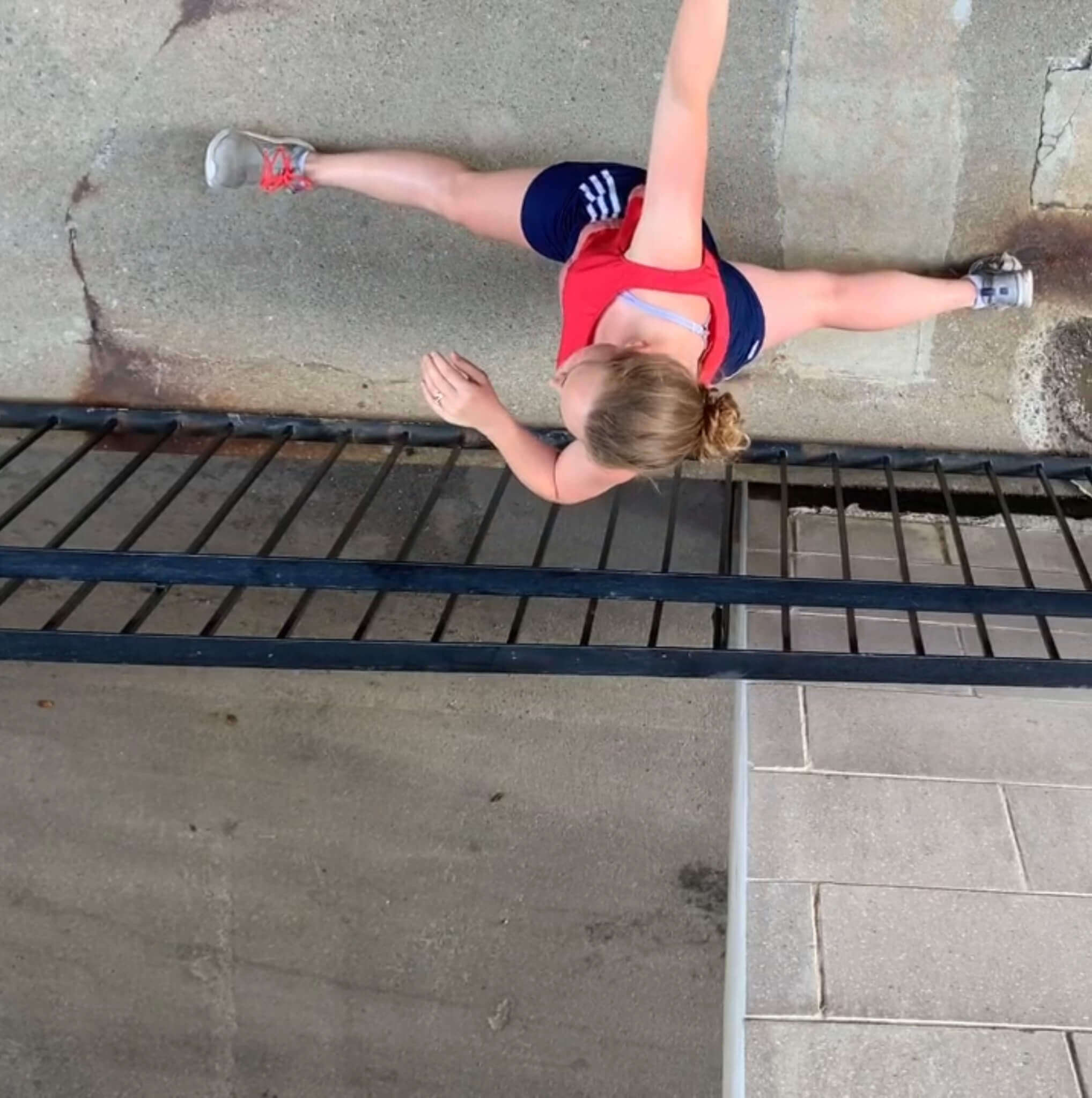 L'interprète en danse Jenna Beaudoin, vue de haut, les jambes allongées sur un plancher de béton.