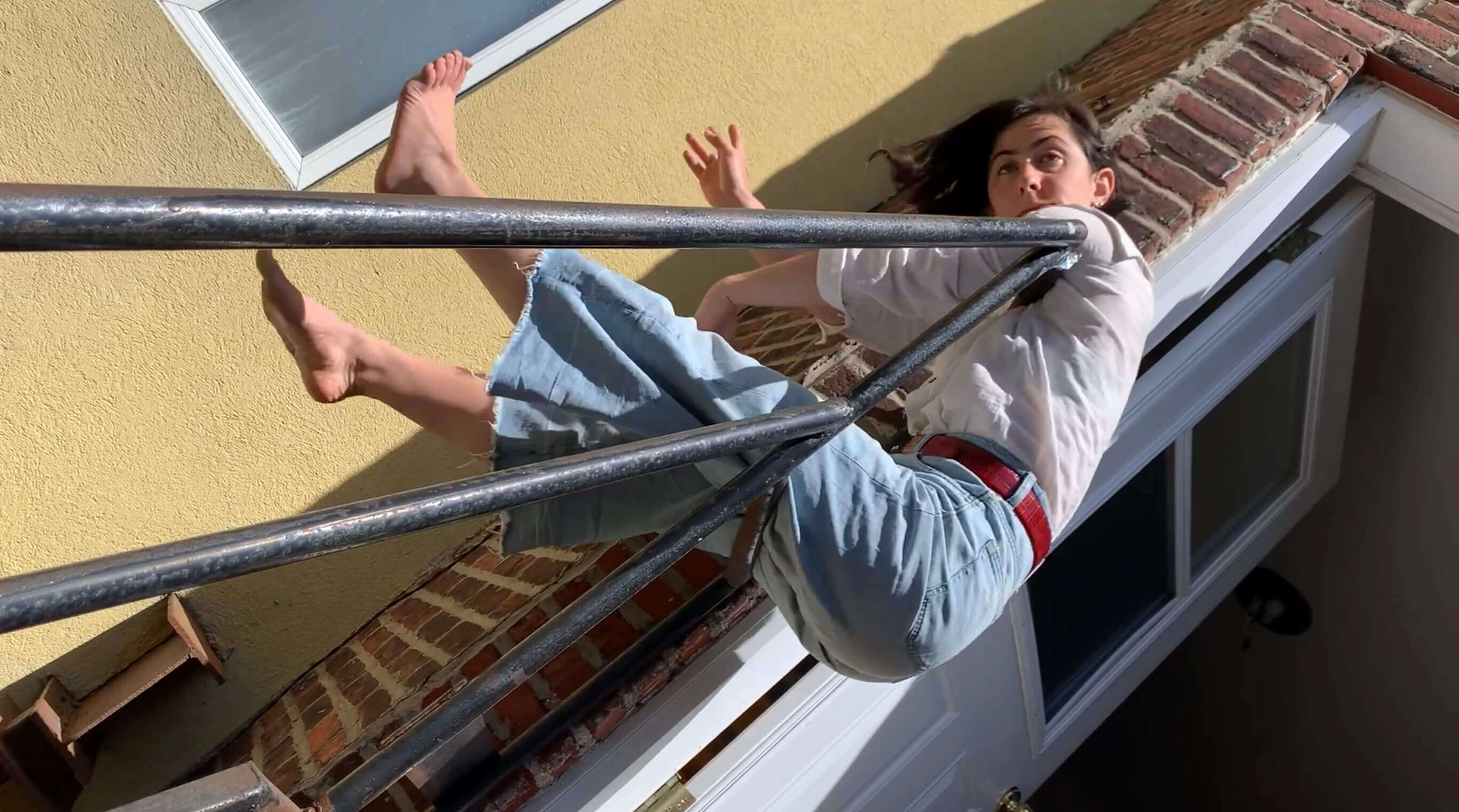 L'interprète en danse Lucy Fandel, pliée en deux sur une rampe comme un bout de tissu qui vole sur une corde à linge.