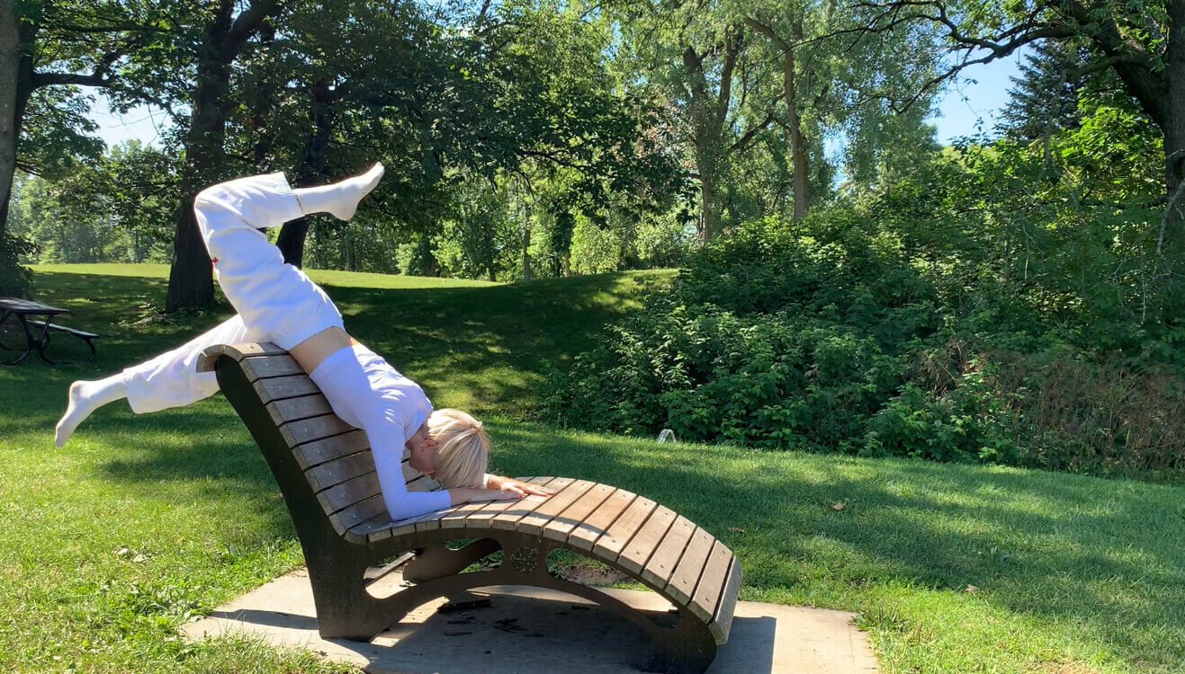 L'interprète en danse Marie-Maxime Ross, habillée tout de blanc, glisse sur une chaise dans un parc.