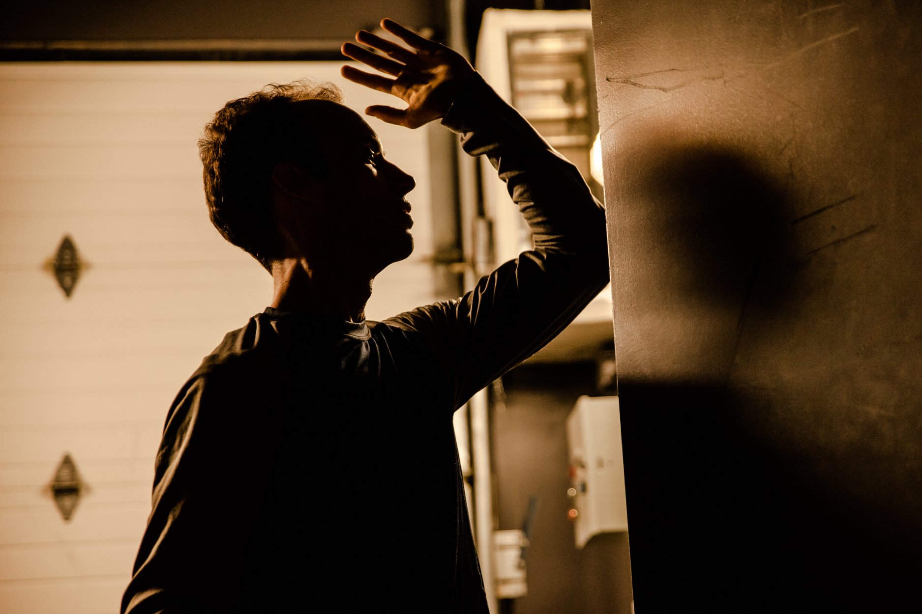 Silhouette du danseur, Guillaume Loslier-Pinard, face à un mur de béton.