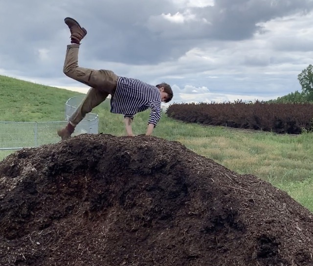 Dancer Lauranne Heulot jumping over a hill of dirt.